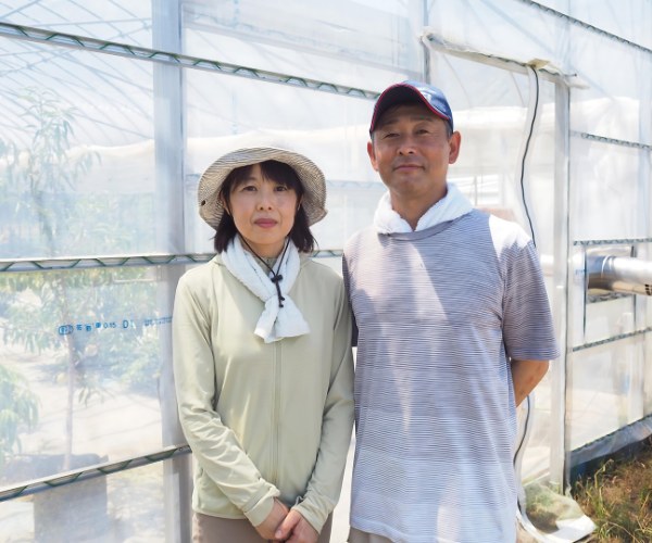 栽培ハウスの前に並んで立つ La Aichi Farm のご夫婦